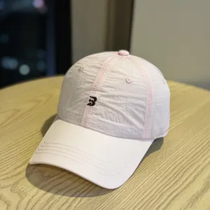Pink embroidered baseball cap detail showing breathable fabric texture and curved brim shape.