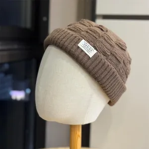 Gedetailleerde close-up van een bruine gebreide muts met textuur en voorste label.