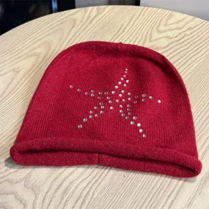 Vista dettagliata del berretto in maglia rossa decorato con stelle di strass.