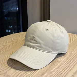 Primer plano de una gorra de béisbol beige minimalista con bordado delicado y corona suave.