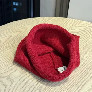 Primo piano dettagliato di un morbido berretto in maglia rossa, con etichetta interna.