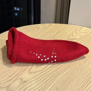 Primo piano del berretto in maglia rossa con motivo a stella di strass per un look casual.