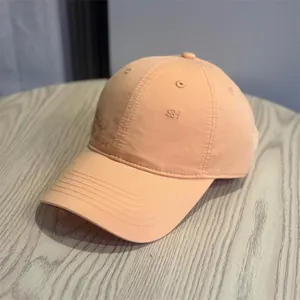 Detail view of the stylish peach pink baseball cap with subtle side embroidery for casual streetwear.