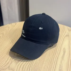 Details of vintage dark baseball cap with white letter embroidery, casual streetwear style.