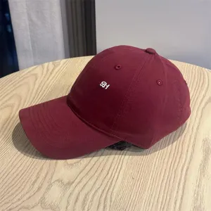 Close-up detail of the vintage burgundy baseball cap featuring white B1 embroidery and fine stitching.