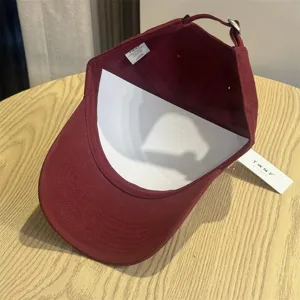 Vintage burgundy baseball cap with white support insert and brand tags, casual streetwear.