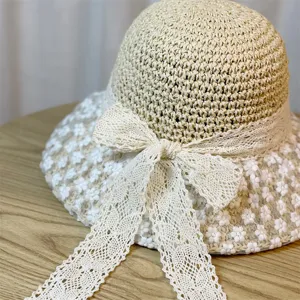 Gedetailleerde close-up van een dames zomer strohoed met delicate witte kanten strik en bloemenrand.