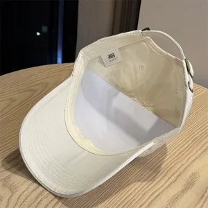Vista detallada de una gorra de béisbol blanca con etiqueta interior y correa ajustable.