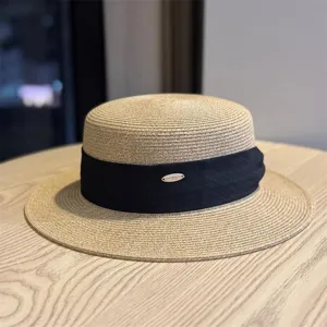 Close-up of the elegant straw boater hat featuring black ribbon and metallic detail accent.