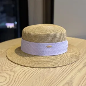 Detailed view of the stylish women's flat-top straw hat with purple ribbon and metal accent.