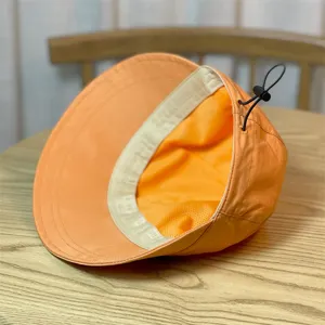 Detalle sombrero de sol naranja, tejido de secado rápido con cordón ajustable y banda.