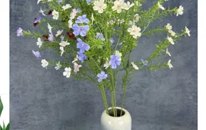 Ramo de flores artificiales de tallo alto con pequeñas flores silvestres y jarrón.