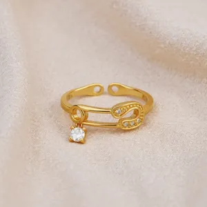 Minimalist gold safety pin open ring with sparkling zircon stones and dangling charm detail.