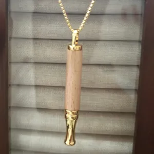Detail shot of wooden anxiety relief breathing whistle necklace with gold metal chain.