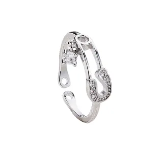 Detailed view of a silver safety pin open ring with sparkling cubic zirconia and hanging charm.