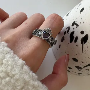 Close-up detail of vintage crown heart purple zircon ring worn on finger elegantly.