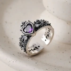 Macro detail close-up shot of a silver gothic crown ring featuring a purple heart zircon stone.