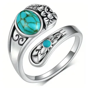 Close-up of vintage silver open ring featuring carved floral leaf motifs and turquoise stones.