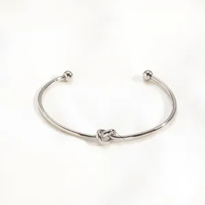 Detailed view of minimalist metal knot cuff bracelet with ball ends, sleek geometric style.