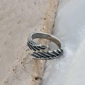 Gros plan détaillé de la bague ouverte plume argentée vintage avec une texture fine.