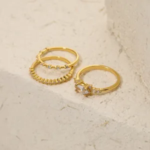 Dettaglio del set di anelli impilabili in rame bagnato oro con zirconi cubici luminosi.