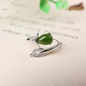 Close-up detailopname van zilveren bladerring met groene steen en sprankelende zirkonia.