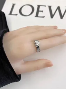 Gros plan d'une bague ouverte vintage en argent avec cœur, détail élégant et chic.