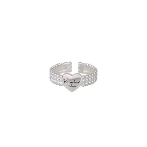 Bague ouverte argentée avec un anneau perlé multicouche et pendentif cœur lettré.