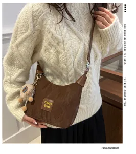 Detailansicht der braunen, slouchy Schultertasche mit niedlichem, flauschigem Plüsch-Anhänger.