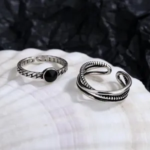 Gedetailleerde close-up van vintage open ringenset met zwarte steen en gedraaid gevlochten ontwerp.