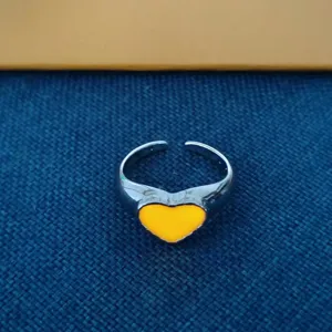 Zilverkleurige open ring met een heldergeel hartmotief in een modieuze minimalistische stijl.
