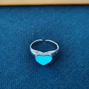Close-up detail van de stijlvolle open legeringsring met een gloeiend blauw hartelement.