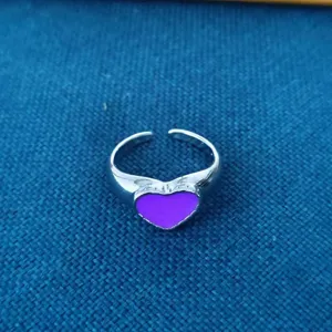 Gedetailleerd overzicht van een stijlvolle zilveren open ring met paars hartvormig sieraad.