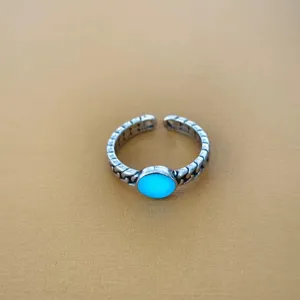 Detailopname van de retro verstelbare zilveren ring met stralende blauwe steen.