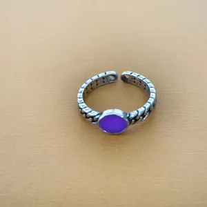 Gedetailleerd shot van retro zilveren open ring met paarse steen en uniek kettingontwerp.