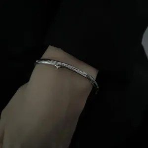 Detail view of a retro thorn open bracelet, minimalist silver metal bangle for daily wear.