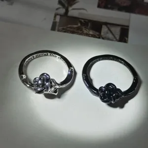 Close up of exquisite metal couple rings featuring rose and thorn design with engraved inner text.