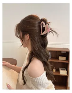 Close-up view of a stylish heart-shaped hair claw clip worn by a model in a cozy room.