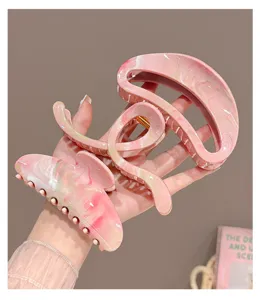 Detailed view of pink marbled hair claw clips, featuring hollow geometric and moon shapes.