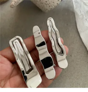 Gros plan d'un ensemble de pinces à cheveux en métal argenté aux designs géométriques.
