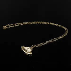 Close-up view of the gold-toned UFO alien spaceship pendant and delicate chain detail.