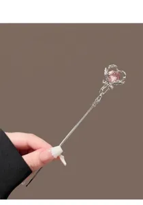 Dettaglio raffinato della bacchetta per capelli con cristallo a cuore rosa scintillante.