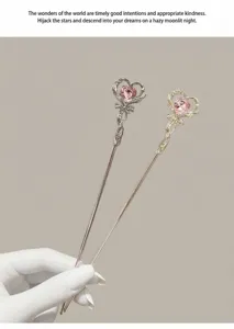 Vista dettagliata dei simpatici bastoncini per capelli a cuore magico con cristallo rosa.