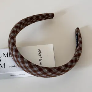 Nahaufnahme des eleganten braunen karierten Stoffhaarbands, zeigt feine Webart.