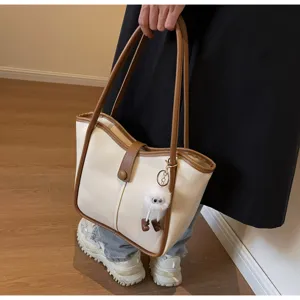 Primo piano di una borsa bicolore chic con manici comodi e un simpatico ciondolo.