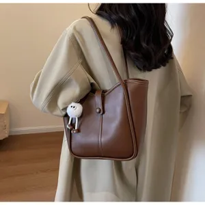 Vista dettagliata della borsa a spalla marrone in pelle PU con ciondolo peluche carino.