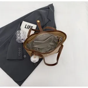 Primo piano dell'interno spazioso della borsa tote bicolore con ciondolo in peluche.