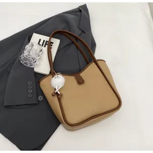 Dettaglio della borsa tote vintage bicolore con ciondolo di peluche, spaziosa borsa a spalla.