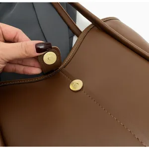 Borsa tote in pelle marrone dettaglio bottone magnetico primo piano con cuciture.