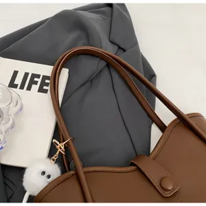 Primo piano della borsa marrone, che mostra una consistenza fine, cuciture e un design elegante.